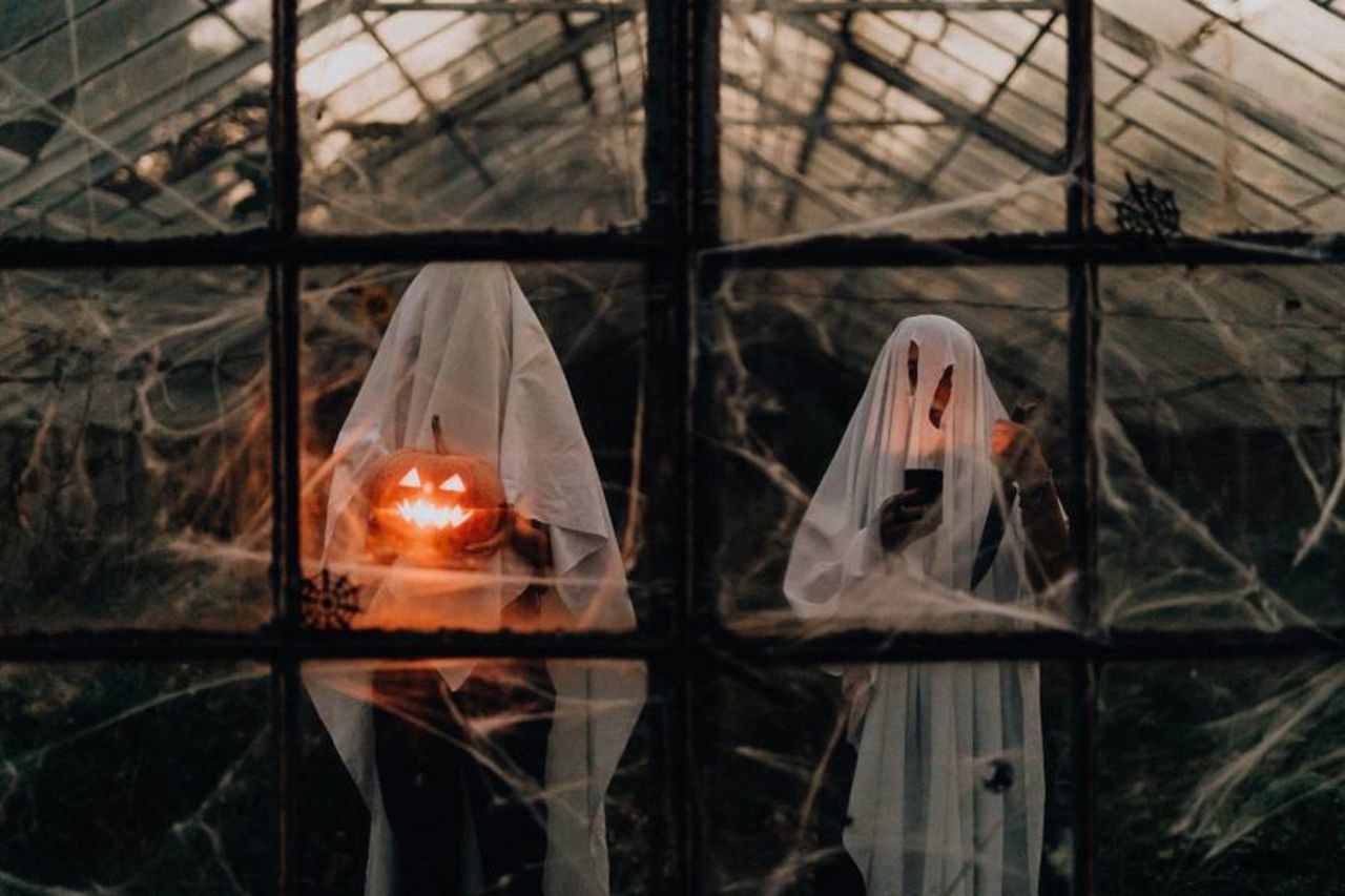 Twee mensen verkleed als spook in een griezelig spookhuis met halloween pompoenen.